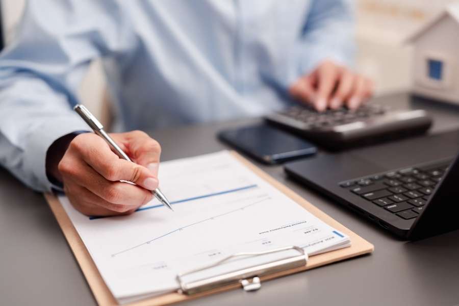 Un professionnel analyse des documents financiers en préparant un placement sur un livret d'épargne réglementée.